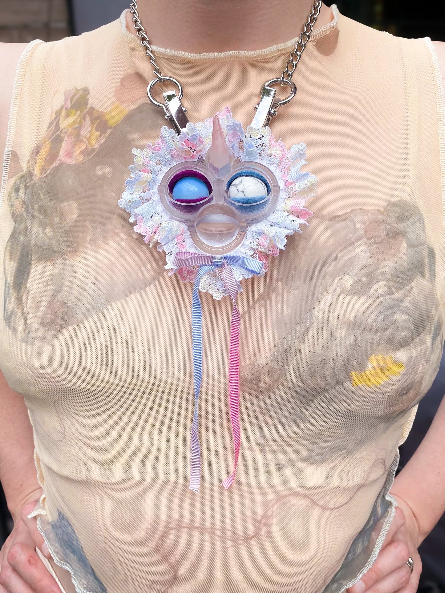clear face pendant with opal and white agate eyes, white lace ruff, pink and blue bow, and rose quartz horn, front view