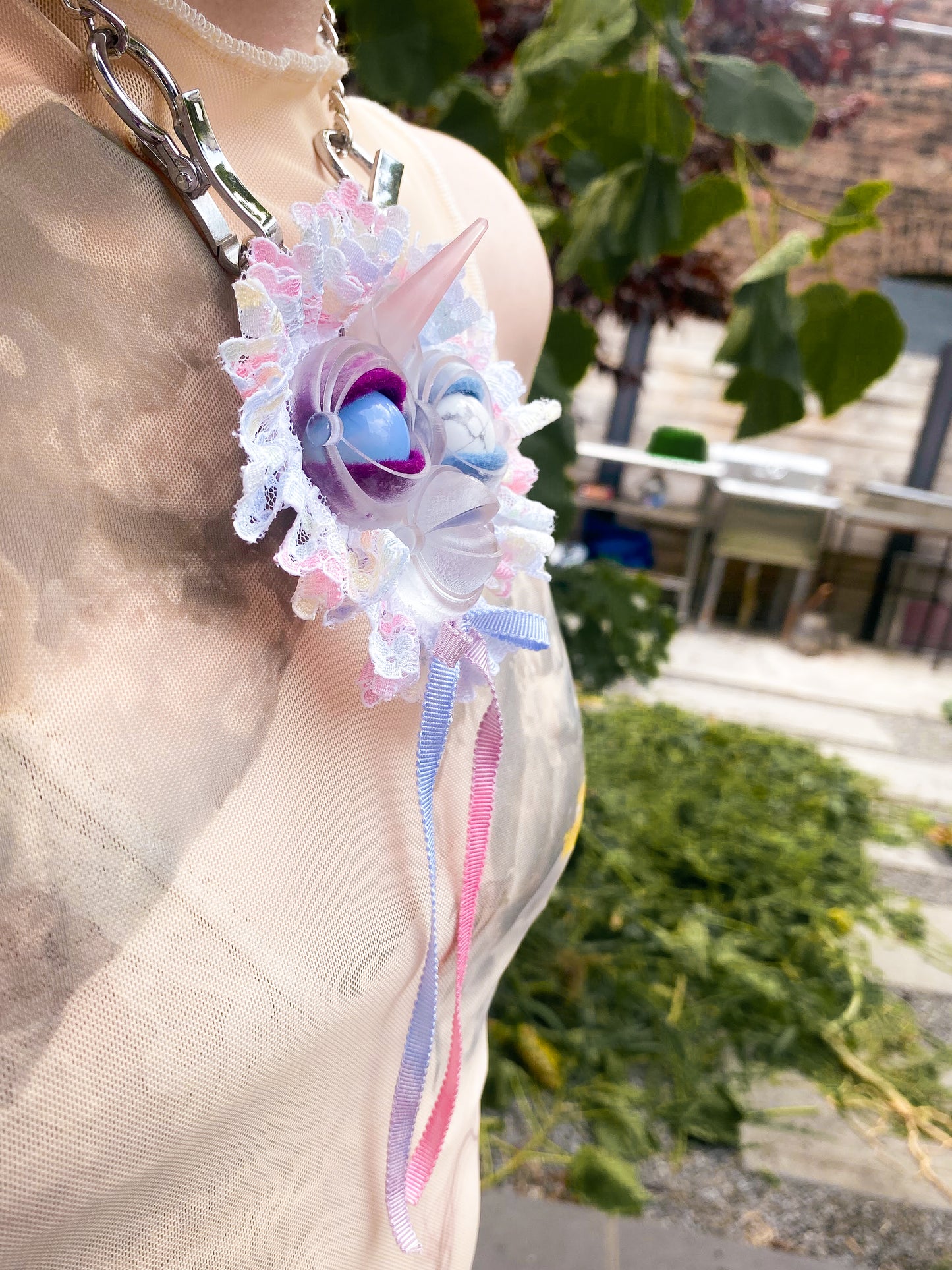 clear face pendant with opal and white agate eyes, white lace ruff, pink and blue bow, and rose quartz horn, 3/4 view