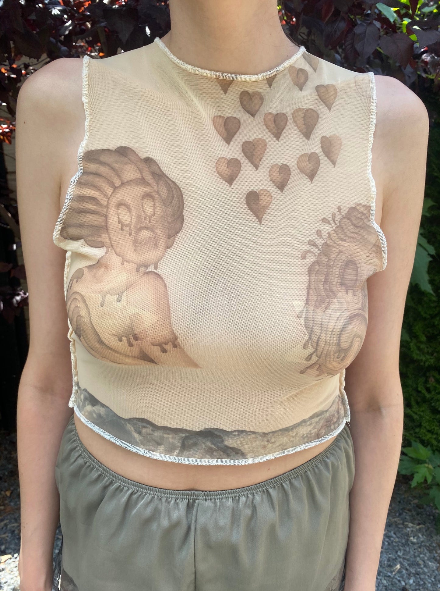 model wears beige mesh crop top with despair faces print