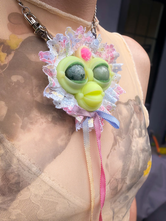 yellow face pendant with mossy agate and green adventurine eyes, pastel multi-colored lace ruff, and pastel rainbow bow, 3/4 view