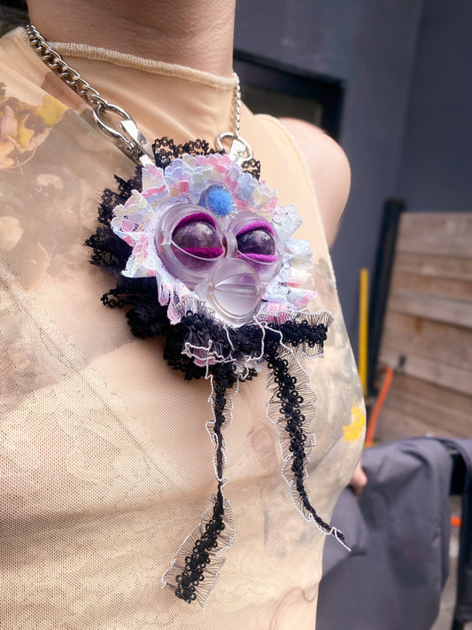 clear face pendant with amethyst eyes, white and black lace ruff, and white and black lace bow, 3/4 view