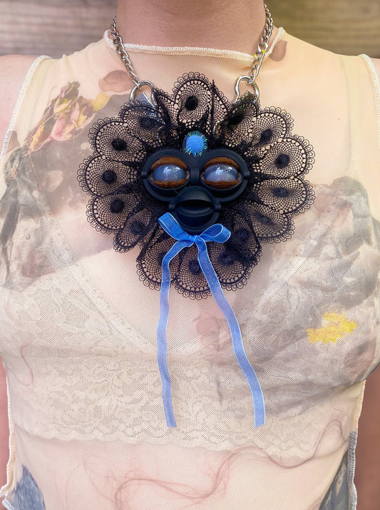 black face pendant with gray agate eyes, black lace ruff, and blue bow, front view