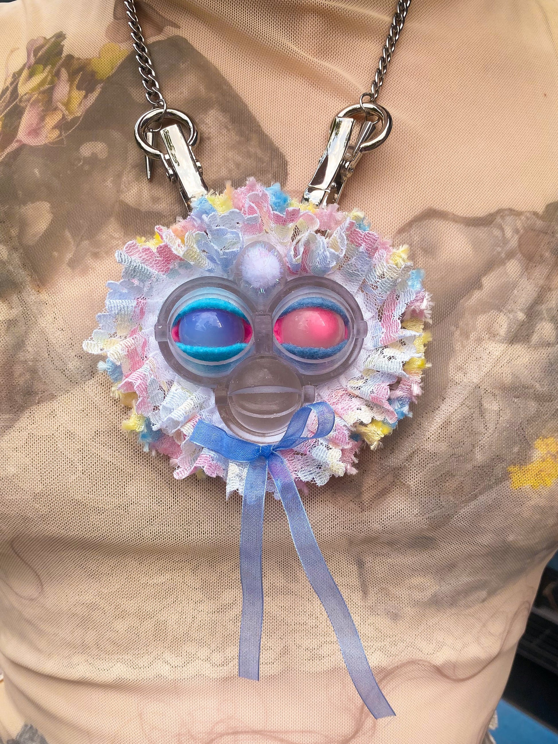 clear face pendant with opal and rose quartz eyes, pastel multi-colored lace ruff, and blue bow, front view