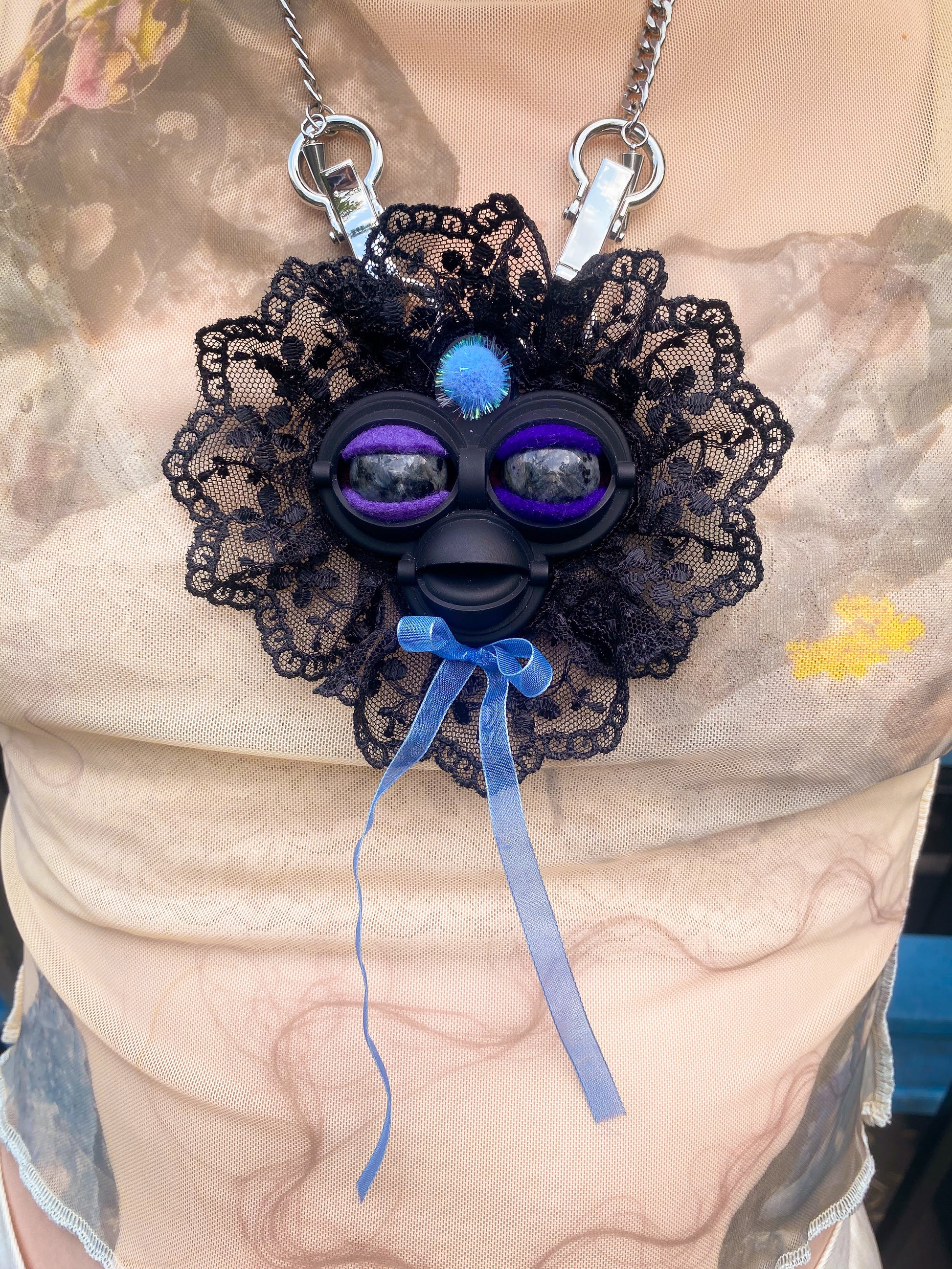 black face pendant with black labradorite eyes, black lace ruff, and blue bow, front view