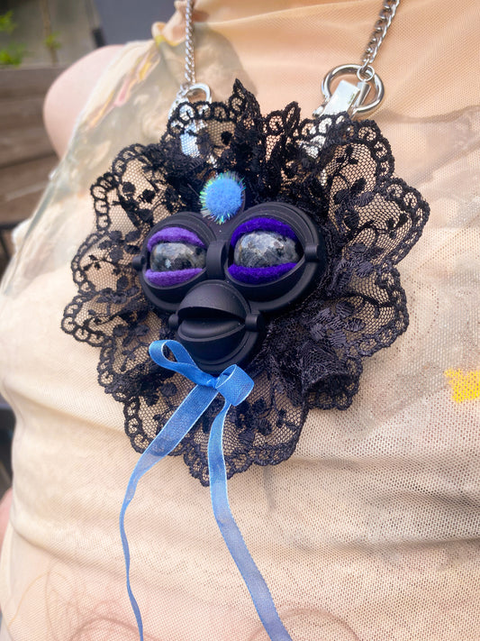 black face pendant with black labradorite eyes, black lace ruff, and blue bow, 3/4 view